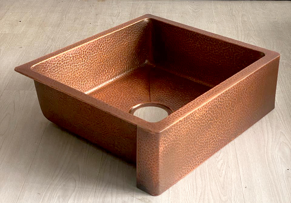 Handmade copper farmhouse sink with warm ambient lighting